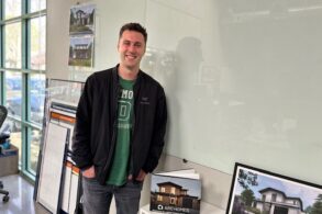 Modular home builder Scott Voulgaris of Mountain View, CA-based Aro homes poses in front of pictures of his firm’s modular homes.