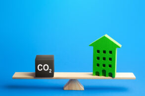 Residential building and CO2 emissions on scales. Greenhouse gas Emissions. Improving energy efficiency, lowering impact on environment.
