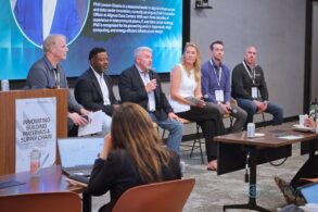 A large panel of speakers addresses a crowd of business people.