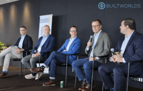 Five men in suits sit on a dais as a panel at a business conference