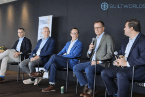 Five men in suits sit on a dais as a panel at a business conference