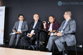 A woman in a maroon blazer speaks into the microphone while three other panelists look on.