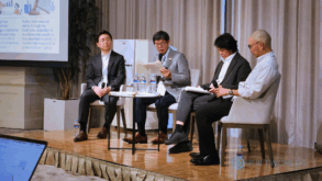 Four men speak on a panel at a business conference.