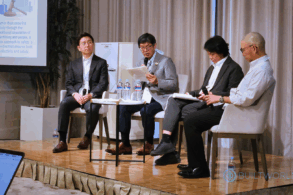 Four men speak on a panel at a business conference.