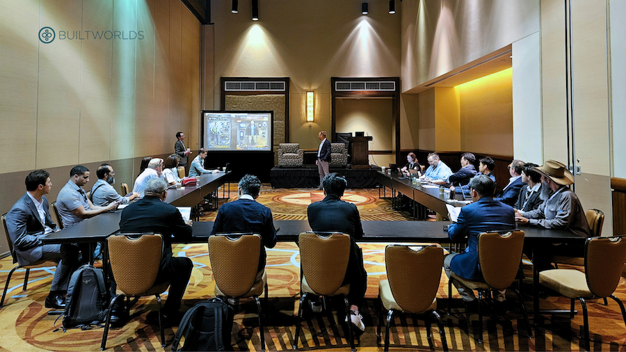 Two men deliver a presentation to a small group sitting in a U-shape configuration.