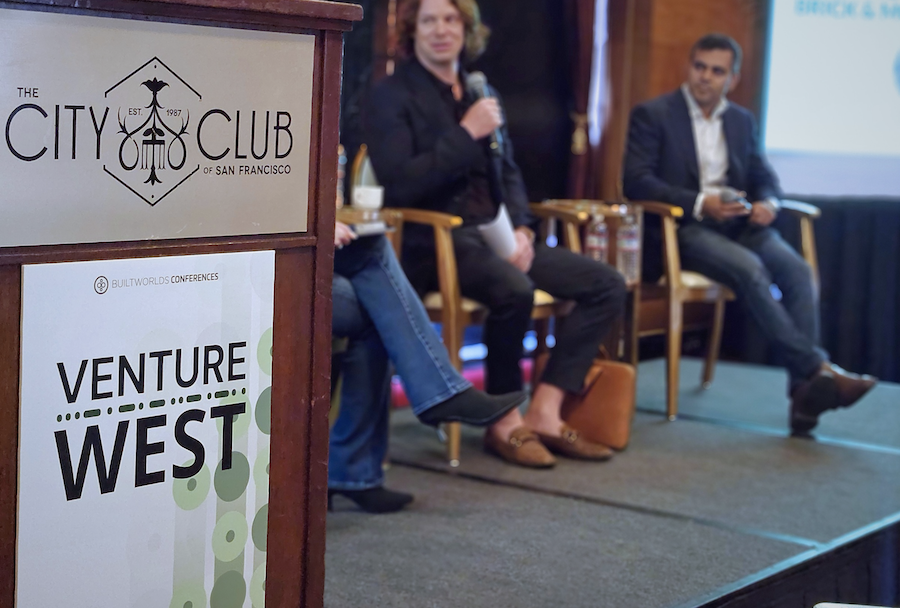 Venture west conference sign with speakers on stage in the background