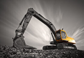 Excavator parked on stone ground against dramatic sky