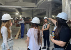 Women wearing white hardhats visit an active jobsite for the construction of a building.